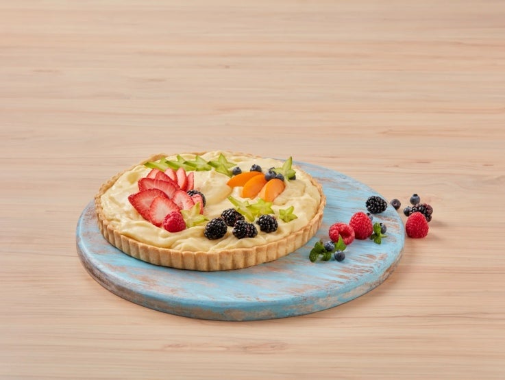 Sobre un plato azul, tartaleta de frutas elaborada con productos LA LECHERA®