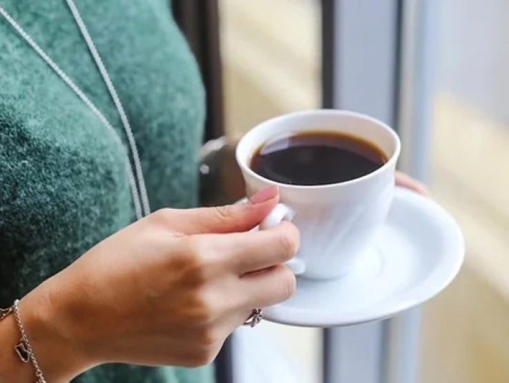 Mano de mujer sostiene un plato y una taza de café elaborada con productos instantáneos NESCAFÉ®