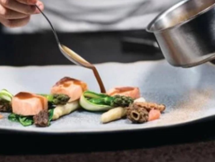 Manos de chef vierten salsa con una cuchara sobre una de las recetas para negocios de NESTLÉ PROFESSIONAL® 