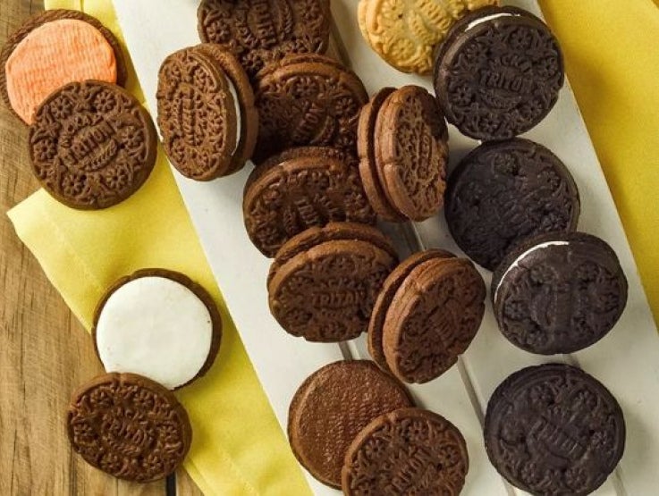 Galletas rellenas de chocolate y vainilla apiladas sobre una tabla de madera blanca y servilleta.