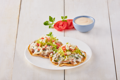 Dos tostadas cubiertas con vegetales y aderezo, elaboradas con ingredientes de un proveedor de lácteos al por mayor.
