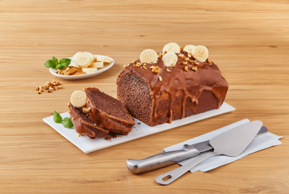 Pan de plátano con cubierto con chocolates y toopings al por mayor, con dos rebanadas cortadas sobre una mesa.