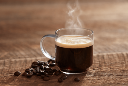 Taza de café humeante con granos de alta calidad, ideal para negocios que buscan un proveedor de café al por mayor.