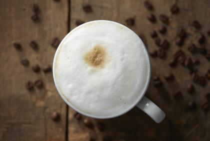 Taza de café humeante con granos de alta calidad, ideal para negocios que buscan un proveedor de café al por mayor