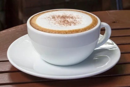 Una taza de capuchino con espuma hecho con productos de un proveedor de café y crema para café al por mayor.
