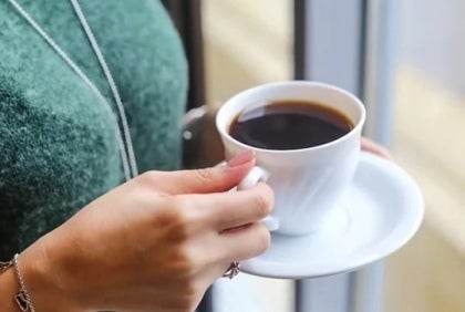 Una persona sostiene una taza de café de un proveedor de café instantáneo para negocios.