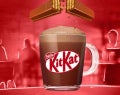 Una taza de chocolate caliente con barras de KITKAT® desmoronándose encima.