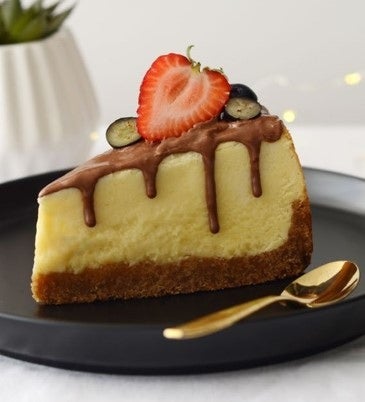 Porción triangular de Cheesecake de Kit Kat adornado con media fresa