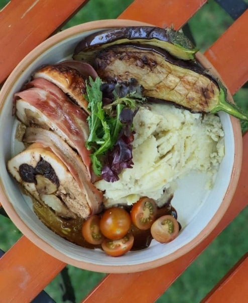 Plato con pechuga de pavo rellena acompañado de puré de berenjenas, salsa, tomates cherry y berenjenas asadas