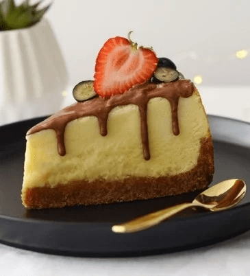 Porción triangular de Cheesecake de Kit Kat decorado con frutillas servido sobre un plato negro