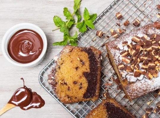 Keke PRINCESA® cortado sobre una malla, y al lado salsa de chocolate y hojas de menta