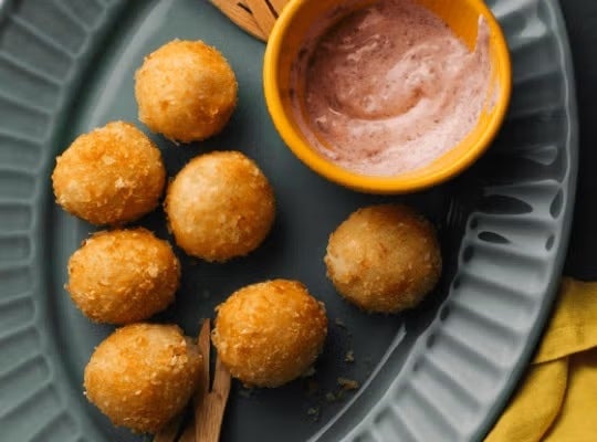 Plato con croquetas de papa redondas y una salsa elaborados con Productos MAGGI®