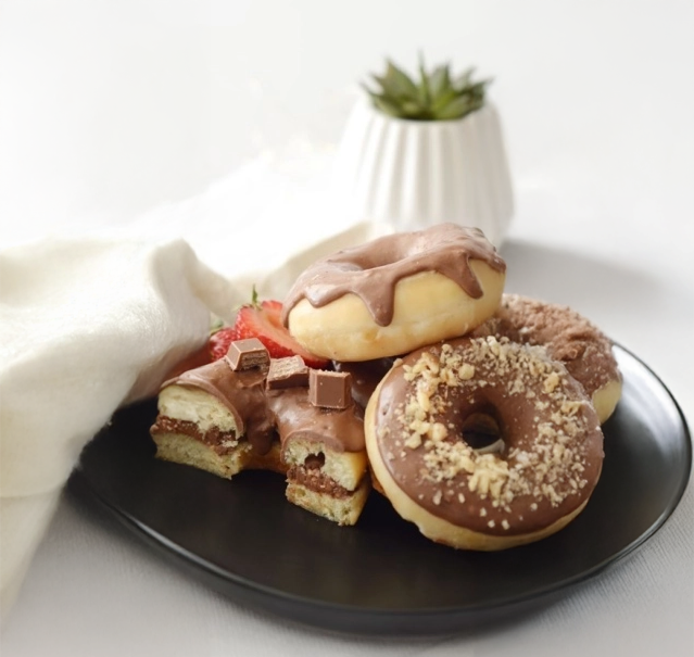 Cuatro donuts bañadas en KitKat spread sobre plato negro