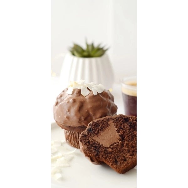 Muffin de chocolate KITKAT® y decorado con virutas de coco, acompañado de una taza de café