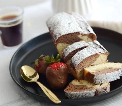 Queque de vainilla y chocolate, espolvoreado con azúcar flor y acompañado de frutillas con chocolate