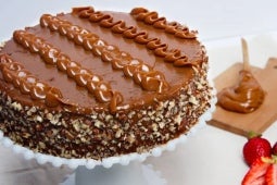 Sobre una mesa, Torta de pecanas decorada con Manjar NESTLÉ® y chocolates