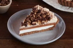 Servido en un plato de porcelana, un trozo de Pie de chocolate PRINCESA® relleno de crema