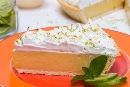 Pie de limón decorado con crema chantilly, hojas de hierbabuena y rodajas de limón