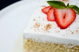 Postre de tres leches de vainilla decorado con chantilly y láminas de fresa