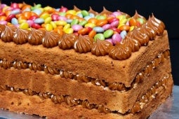 Torta con relleno de manjar NESTLÉ® y cubierta con LENTEJAS® Mini