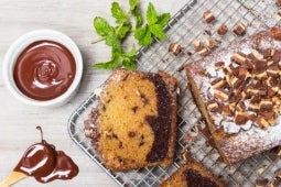 Keke PRINCESA® cortado sobre una malla, y al lado salsa de chocolate y hojas de menta