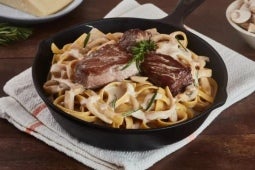Lomo Strogonoff servido en una sartén sobre fetuccini y salsa blanca elaborado con NESTLÉ® Crema de leche
