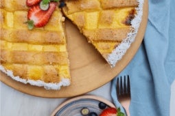 Sobre una base de madera, una Tarta de ricotta y NESTLÉ® Manjar Dulce de Leche sin un trozo