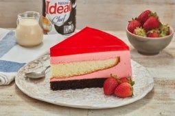 Trozo de Torta Helada con Gelatina de frutos rojos y fresas servidas a la mesa junto a la IDEAL® Cremosita