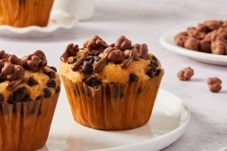 Muffins con chispas de chocolate en un plato blanco, cubiertos con trozos de chocolate crujientes.