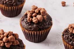 Muffins de chocolate cubiertos con racimos de chocolate crujientes sobre una superficie ligera.