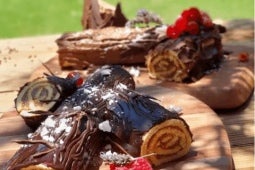 Troncos de Navidad rellenos de Manjar NESTLÉ® y cubiertos de chocolate, servidos en tablas