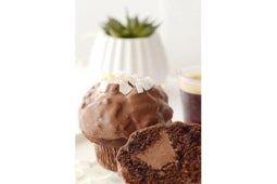 Muffin de chocolate KITKAT® y decorado con virutas de coco, acompañado de una taza de café