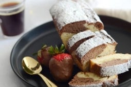 Queque de vainilla y chocolate, espolvoreado con azúcar flor y acompañado de frutillas con chocolate