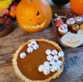 Pie de zapallo decorado con suspiros junto a una calabaza de Halloween, frutillas y golicinas