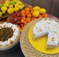 Pie de limón y maracuyá con merengue suizo junto a dos bandejas con limones, mandarinas y fresas
