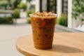 Vaso Transparente NESCAFÉ con receta Mokacciono Hot Over Ice sobre una mesa en el exterior de una confiteria
