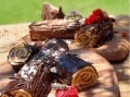 Troncos de Navidad rellenos de Manjar NESTLÉ® y cubiertos de chocolate, servidos en tablas