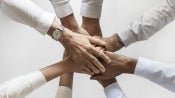 Personas juntan sus manos en el centro como un equipo