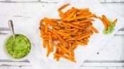 Plato de porcelana con papas fritas en bastones acompañadas de una taza de guacamole