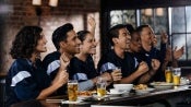 Grupo de amigos festejan sentados en la barra de un gastrobar donde hay comida y bebidas