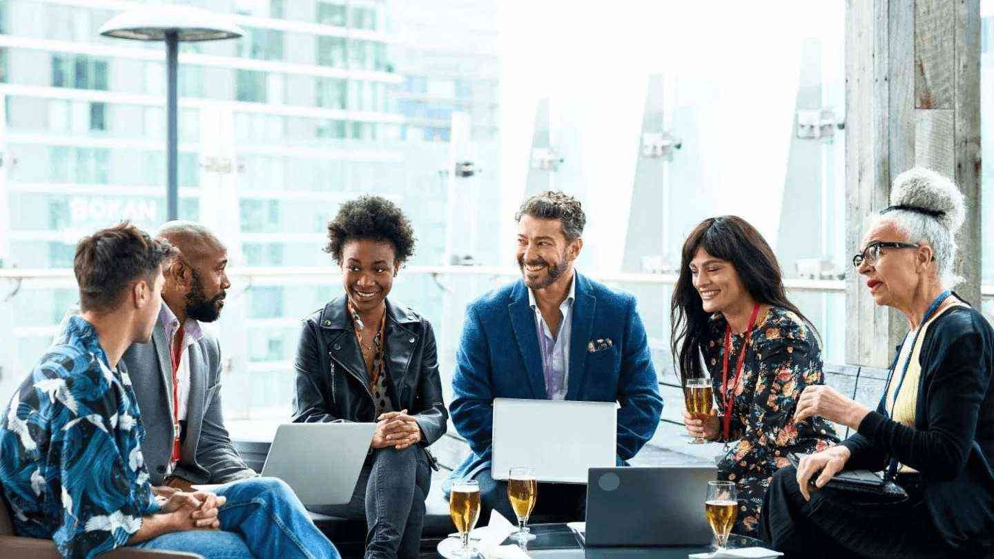 Grupo de seis personas sonrientes reunidas alrededor de una mesa