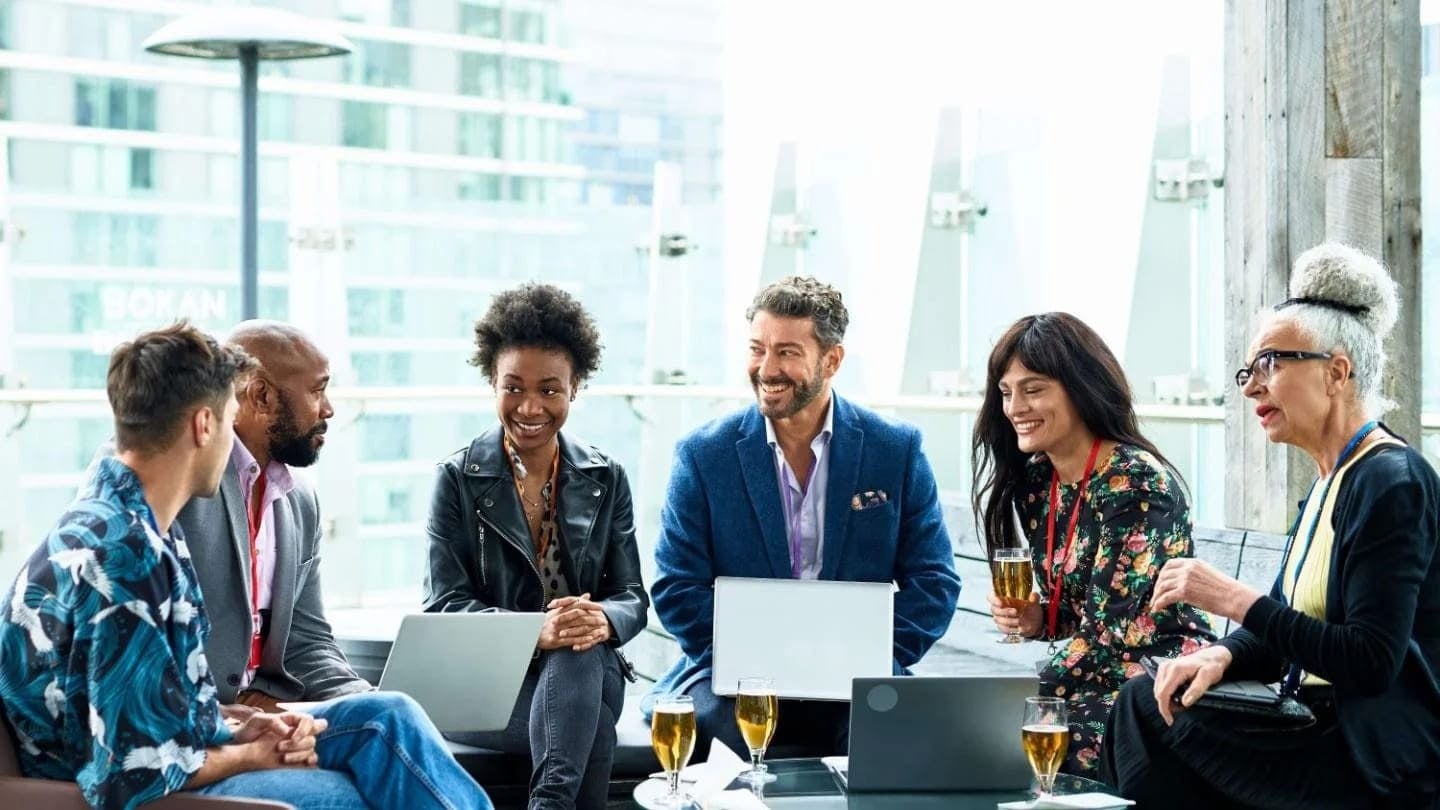 Grupo de mujeres y hombres sonriendo reunidos alrededor de una mesa