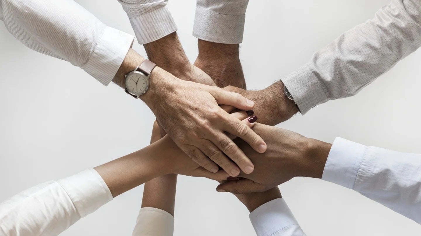 Personas juntan sus manos en el centro como un equipo