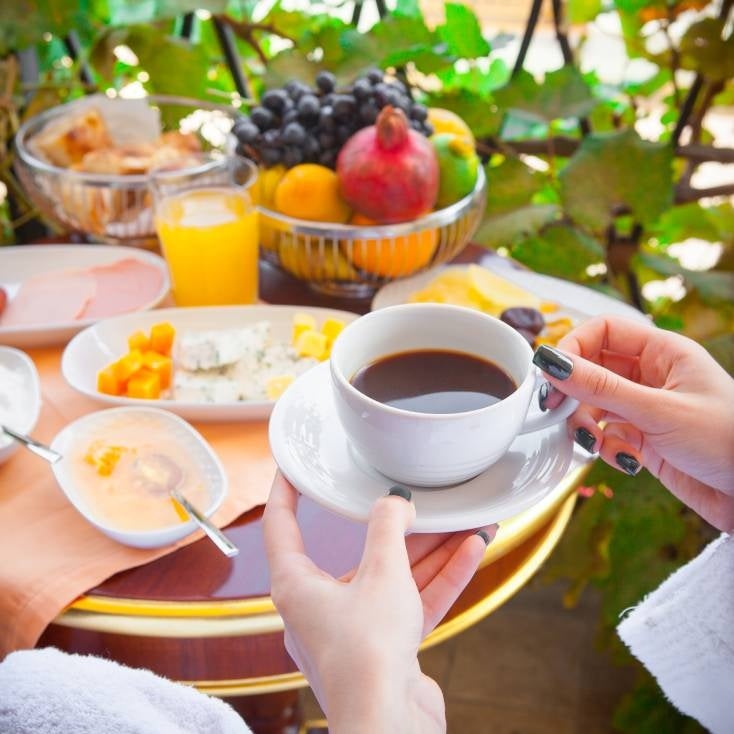 Huésped tomando café y un desayuno con huevos y fruta
