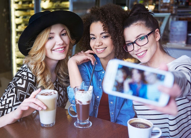 Tres influencers se toman fotos para sus redes sociales en una cafetería que aporta a un plan de marketing gastronómico