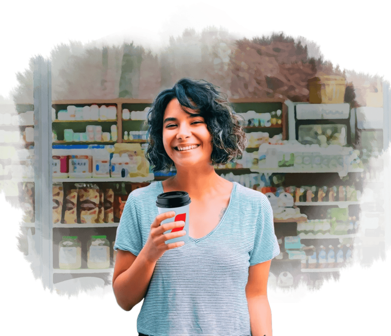 A las afueras de una cafetería, mujer sostiene un vaso de NESCAFÉ®