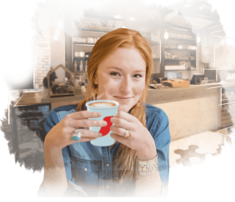 Mujer sostiene un vaso de NESCAFÉ® en una cafetería