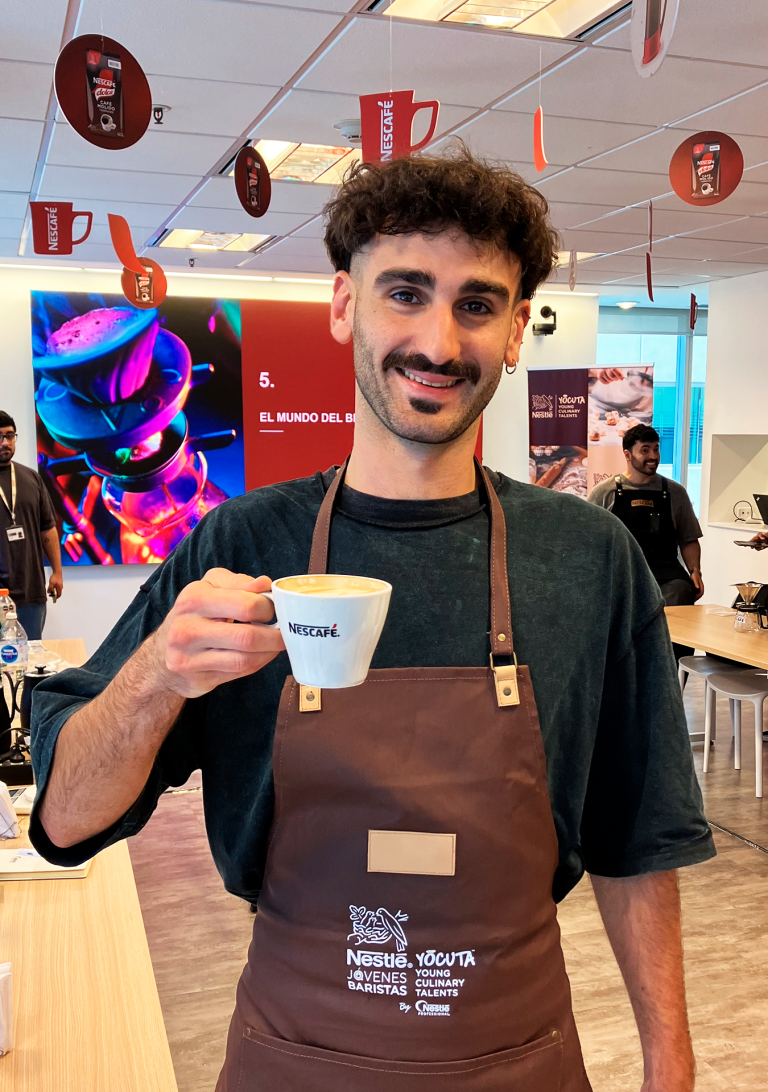 Joven aprendiz del programa YOCUTA de Nestlé, sostiene taza de café en reapertura de 2025