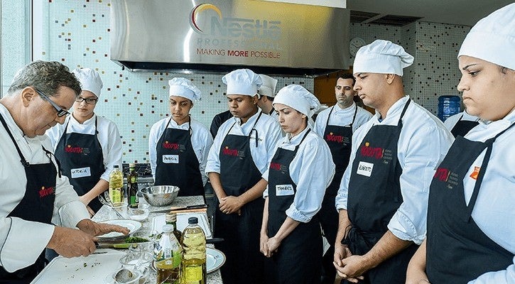Chef instruyendo a grupo de estudiantes en cocina profesional durante formación del Programa YOCUTA