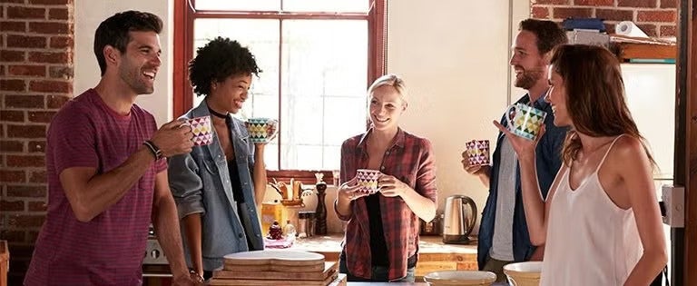 Grupo de personas conversando y tomando bebidas calientes en un espacio de cocina